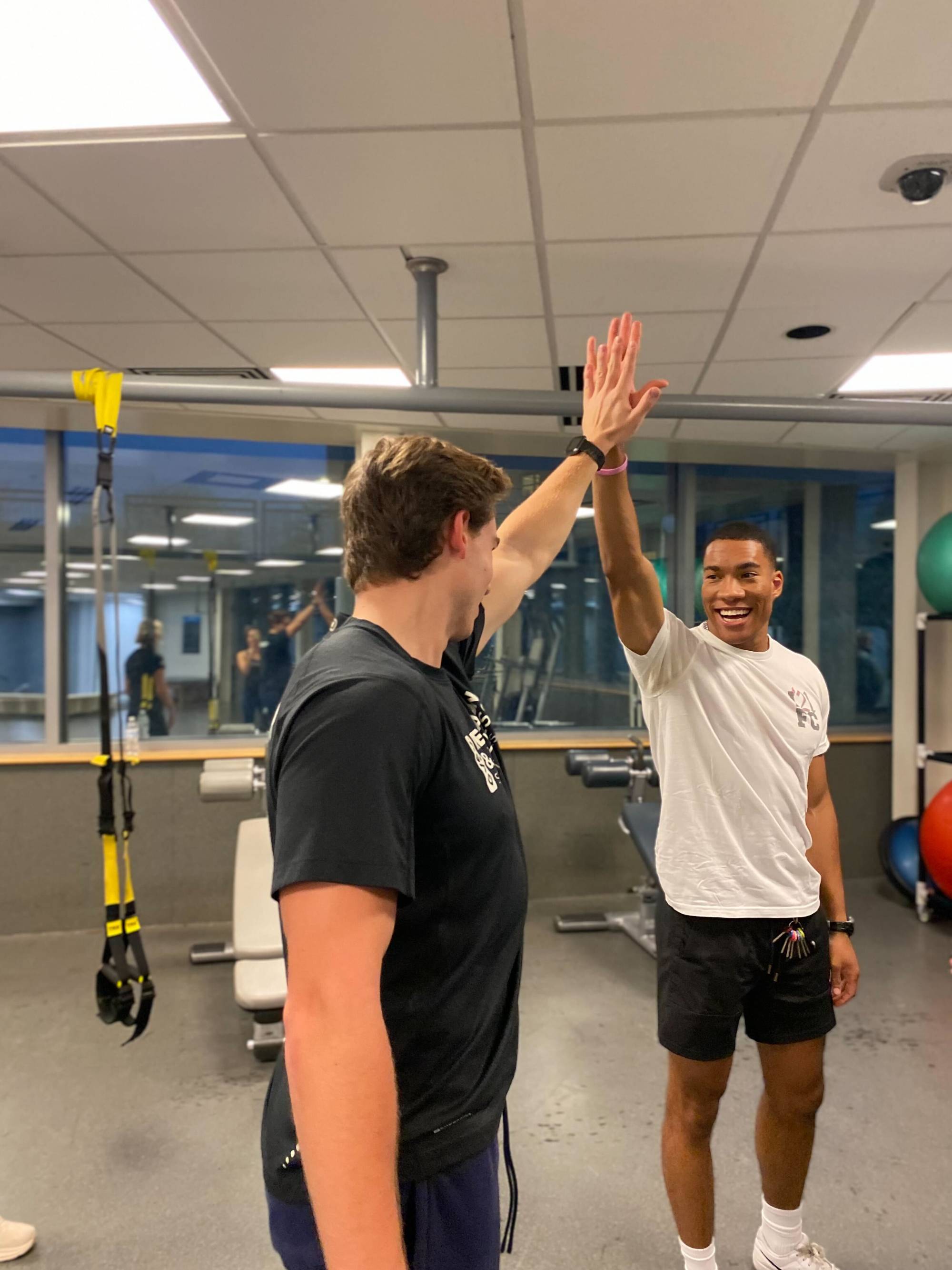 Instructor and student on Spin bikes doing a high five.